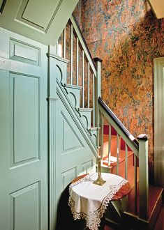 a table with a white cloth on it next to a green door and some stairs