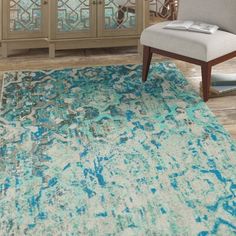 a blue and white rug in a living room next to a chair with a vase on it