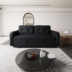 a black couch sitting on top of a white rug in a living room next to a table