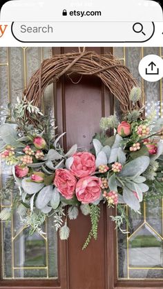 a wreath with pink flowers and greenery is hanging on the front door