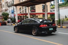 a black car driving down a street next to tall buildings