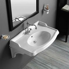 a white sink sitting next to a mirror in a bathroom on top of a wooden floor