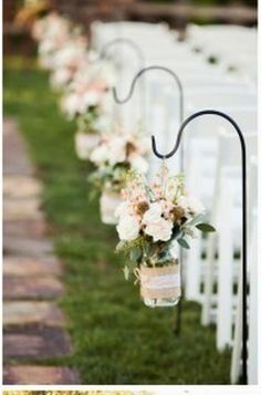 rows of white chairs lined up with vases filled with flowers