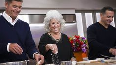 two men and a woman are preparing food in the kitchen while one man is smiling