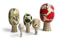 three wooden birds standing next to each other in front of an egg shaped like a tree