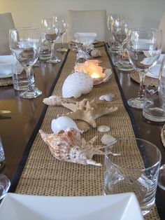 the table is set with seashells and wine glasses for dinner guests to enjoy