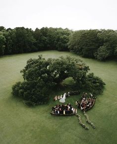 an aerial view of a wedding ceremony in the middle of a large field with trees