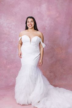 a woman in a white wedding dress posing for the camera with her hands on her hips