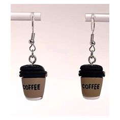 two coffee cups hanging from hooks with the word coffee written on them, one being held by a pair of earrings