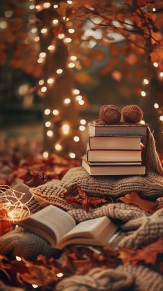 an open book sitting on top of a pile of books next to a lit tree