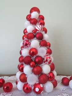 a red and white christmas tree with ornaments on the top is sitting on a table