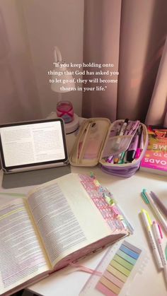 an open book sitting on top of a table next to some pens and pencils