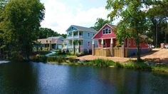 several houses on the edge of a body of water with trees in front of them