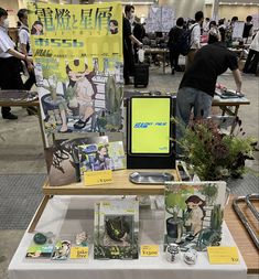 a table with various items on it and people standing around in the background looking at them