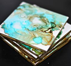 three square coasters are stacked on top of each other with blue and green designs