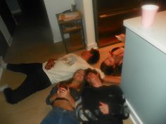 four people are laying on the floor with their arms around each other