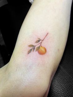 a small orange on the arm with leaves and an arrow in it's center