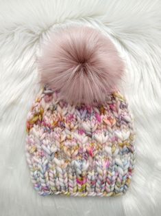 a knitted hat with a pink pom - pom on top