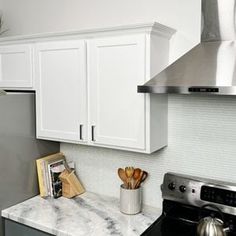 a kitchen with white cabinets and marble counter tops, stainless steel appliances and an oven