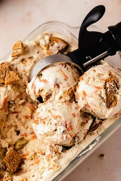 two scoops of ice cream in a glass container with black handles and nuts on top