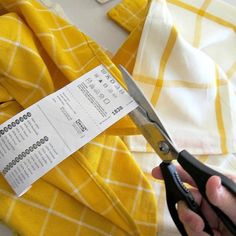 a person holding a pair of scissors next to a yellow and white checkered shirt