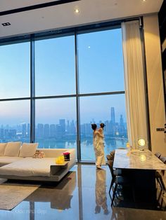 a woman standing in front of a large window looking out at the cityscape