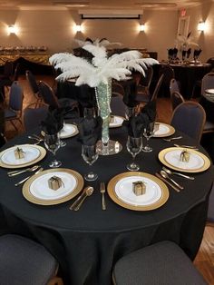 a table set with black and white plates, silverware, and centerpieces