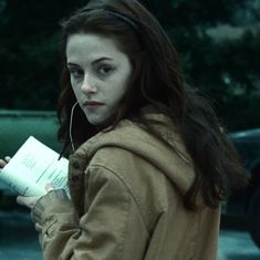 a young woman is holding a book and listening to headphones