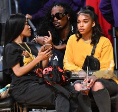 two young women sitting next to each other in the stands at a basketball game, one is