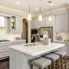 a kitchen with white cabinets and gray stools