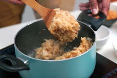 a person stirring food in a pot with a wooden spoon