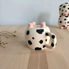 two ceramic mugs with black and white polka dots on them sitting on a wooden table