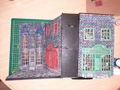 a paper model of a building with red windows and green shutters on the front