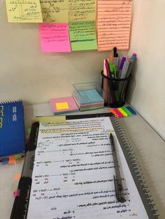 a notepad and pen sitting on top of a desk with sticky notes attached to it