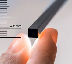 a person holding a black object in their left hand and measuring it with a ruler