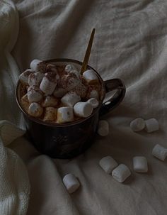 a cup filled with marshmallows on top of a bed