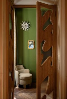 an open door leading to a green room with a chair and mirror on the wall