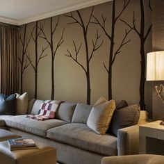 a living room with couches, lamps and trees painted on the wall behind it