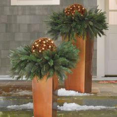 two tall metal planters with christmas decorations on them in front of a door way