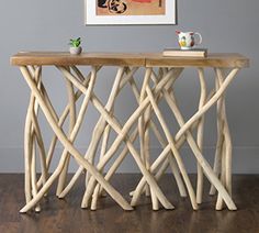 a table made out of branches with a book on top of it and a vase in front of it