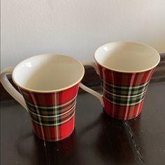 two red and black plaid coffee cups sitting on top of a counter next to each other