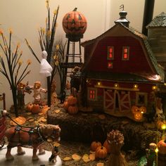 a table topped with lots of fake pumpkins next to a red barn and other decorations