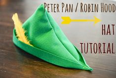 a green hat sitting on top of a wooden table next to a sign that says peter pan / robin hood