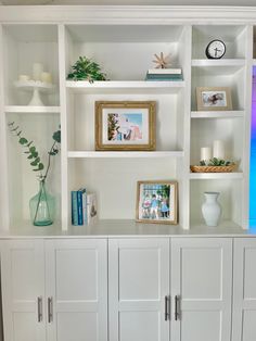 a white bookcase filled with lots of books next to a vase and two framed pictures