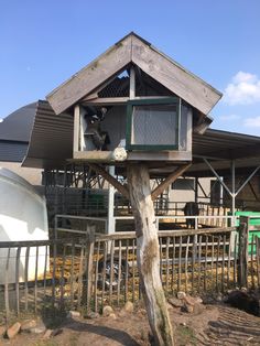 a tree house built into the side of a wooden pole in front of a building