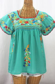 "* Ornate hand embroidery and smocking with hand crocheted trim on the neck and open sleeve hems, available here in MINT with SPRING FIESTA MIX embroidery. * Light, gauzy and semi-sheer 100% cotton throughout; wear it billowy and flowing in the bohemian style, or belted for a more fitted look. * Dyed, distressed and embroidered by hand for an authentic, retro-vintage and boho-chic hippie vibe.  * Our colorful and ornate floral embroidery patterns are a faithful tribute to the traditional hippie Mexican Peasant Blouse, Embroidery Light, Mexican Blouse, Floral Embroidery Patterns, Open Sleeve, Mexican Dresses, Green Spring, The Bohemian, Muslin Fabric