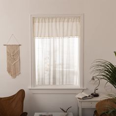 a living room with a chair, window and potted plant in front of the window