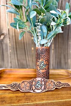 a vase filled with green leaves on top of a wooden table