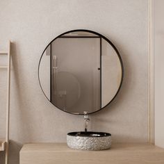 a round mirror hanging on the wall next to a sink in a room with white walls