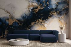 a blue couch sitting in front of a wall with gold and black paint on it